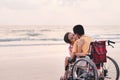 Mother and special child on wheelchair on the sea beach with sunset Royalty Free Stock Photo