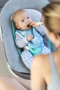 Mother spoon feeding her baby boy infant child in baby chair with fruit puree. Baby solid food introduction concept. Royalty Free Stock Photo