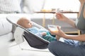 Mother spoon feeding her baby boy infant child in baby chair with fruit puree. Baby solid food introduction concept. Royalty Free Stock Photo