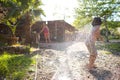 Mother sprays a child with a hose in the courtyard of the house, Boy drenched in water on a hot sunny day