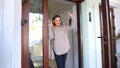 Mother standing by door and waving hand to children walking to school, goodbye