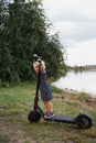 Mother standing near electric scooter in park with her daughters