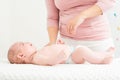 Mother standing next to bed with her newborn baby boy lying on his back. Baby boy on a bed wearing a nappy looking at the mother. Royalty Free Stock Photo