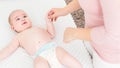 Mother standing next to bed with her newborn baby boy lying on his back. Baby boy on a bed wearing a nappy looking at the mother. Royalty Free Stock Photo