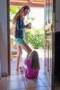 Mother standing talking to her daughter sitting in doorway of a