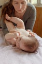 Mother stands next to the child. Massage for the baby. Four month old baby smiling doing gymnastics