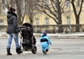 Mother with stroller walking near little son