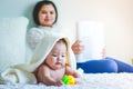 Mother takes care of the baby who is playing on the bed.