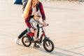 Mother takes care of a child, training to ride a bicycle, running after her son in a public park Royalty Free Stock Photo