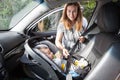 Mother takes care about her newborn daughter in a car, fastening the infant car safety seat Royalty Free Stock Photo