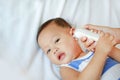 Mother takes temperature for baby boy with ear thermometer on bed at home Royalty Free Stock Photo