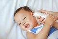 Mother takes temperature for baby boy with ear thermometer on bed at home Royalty Free Stock Photo