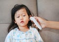 Portrait of child girl with a ear thermometer measuring Royalty Free Stock Photo