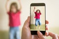 Mother taking photo of jumping baby girl with her mobile phone