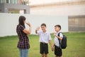 Mother taking sons to school together, hand wave good bye