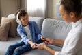 Mother taking tablet from reluctant child with headphones