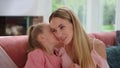 Mother talking with daughter at home. Girl whispering secret on woman ear Royalty Free Stock Photo