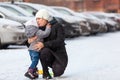 Mother talking with her little child, embracing and kissing after falling dawn on ice at winter season