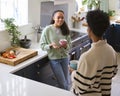 Mother Talking With Teenage Daughter At Home In Kitchen Drinking Hot Drinks Together Royalty Free Stock Photo