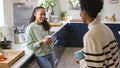 Mother Talking With Teenage Daughter At Home In Kitchen Drinking Hot Drinks Together Royalty Free Stock Photo