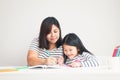 Mother taught homework to the little daughter sitting at the white table in the room. The concept of education for elementary