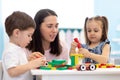 Mother or teacher with children building block toys at home or day care. Kids playing with color blocks. Educational Royalty Free Stock Photo