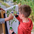 Mother teaches boy son to paint on canvas. Woman teacher artist paints with a child on paper nature and trees by the river Royalty Free Stock Photo