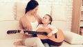 Mother Teaches Daughter Playing Guitar at Home. Royalty Free Stock Photo