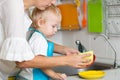 Mother teaches little son dish cleaning in domestic kitchen Royalty Free Stock Photo