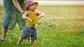 Mother teaches to walk happy toddler baby boy in nature on green gras Royalty Free Stock Photo