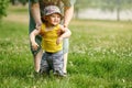 Mother teaches to walk happy toddler baby boy in nature on green gras Royalty Free Stock Photo