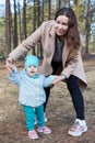 Mother teaching baby to walk in the park, first step of adorable little girl with mom assistance Royalty Free Stock Photo