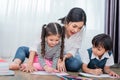 Mother teaching children in drawing class. Daughter and son painting with colorful crayon color in home. Teacher training students