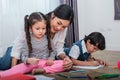 Mother teaching children in drawing class. Daughter and son painting with colorful crayon color in home. Teacher training students Royalty Free Stock Photo