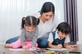 Mother teaching children in drawing class. Daughter and son painting with colorful crayon color in home. Teacher training students Royalty Free Stock Photo