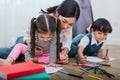 Mother teaching children in drawing class. Daughter and son painting with colorful crayon color in home. Teacher training students Royalty Free Stock Photo