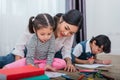 Mother teaching children in drawing class. Daughter and son painting with colorful crayon color in home. Teacher training students Royalty Free Stock Photo