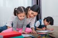 Mother teaching children in drawing class. Daughter and son painting with colorful crayon color in home. Teacher training students