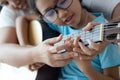 Mother teaching the daughter learning how to play acoustic classic guitar for jazz and easy listening song select focus shallow