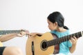 Mother teaching the daughter learning how to play acoustic classic guitar for jazz and easy listening song select focus shallow