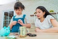 Mother teaching daughter on financial saving and planing using saving jar and piggy bank with real moner, for Money and wealth