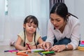 Mother teaching girl in drawing class. Daughter painting with colorful crayon color in home. Teacher training students in art Royalty Free Stock Photo