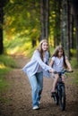 Mother teaching her daughter cycling in a forest outdoors Royalty Free Stock Photo