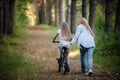 Mother teaching her daughter cycling in a forest outdoors Royalty Free Stock Photo