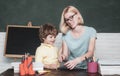 Mother teaching her son in classroom at school. Funny little child and young female teacher having fun on blackboard Royalty Free Stock Photo