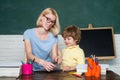Mother teaching her son in classroom at school. Funny little child and young female teacher having fun on blackboard Royalty Free Stock Photo