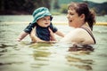 Mother teaching infant baby son to swim in lake Royalty Free Stock Photo