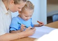 Mother teaching little daughter during homeschool class at home. Cute little caucasian girl learning how to read and Royalty Free Stock Photo