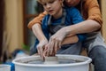 Mother teaching son how make pottery on pottery wheel. Child creative activities and art. Boy making pottery, having fun