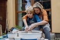 Mother teaching son how make pottery on pottery wheel. Child creative activities and art. Boy making pottery, having fun